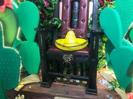 Abstract plastic funny beautiful joyful Mexican cacti with flowers and a chair with a sambrero hat. The background photo