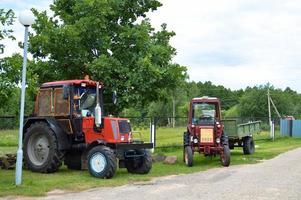 dos tractores de construcción agrícola profesionales rojos con ruedas grandes con una banda de rodadura para arar el campo, tierra, transporte de mercancías foto