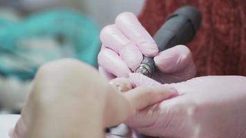 chiodo cura. ragazza fare manicure. bellezza salone. nel il rosa medico guanti. vicino su. video