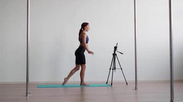 Athletic woman fitness trainer conducts workout online by filming video on a mobile phone. Remote learning and training. Remote business concept.