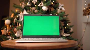 Laptop with Green Screen and Colored Key against the Background of a Christmas Tree. New Year. Camera Moves Smoothly to the Side. video