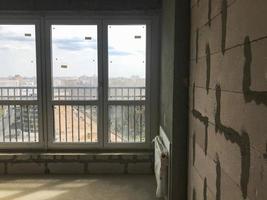 una gran ventana francesa de vidrio panorámico con un perfil de plástico en un edificio nuevo con un diseño libre, en un apartamento sin reparación de edificios foto