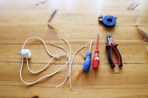 Electrical circuit with wires and spare parts, installation equipment, pliers, blue electrical tape, screwdrivers on the table photo