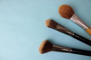 Beauty box, crumbly matte mineral powder with a special brown beautiful wooden brushes from natural nap for makeup on a warm blue background. Flat lay. Top view photo