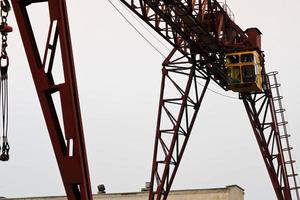 grúa de pórtico de metal grande de hierro industrial con un gancho montado en los soportes para levantar y transportar carga pesada, moviéndose a lo largo de los rieles en la fábrica. la grúa es de tipo puente foto