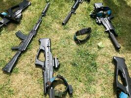Black iron metal army military machine guns, small arms for soldiers with silencers lie on the background of green grass photo