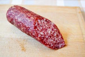 Delicious, appetizing red sausage salami on a birch cutting board photo