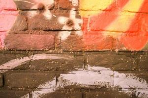 A gray, red, yellow and white brick wall painted with paint. Texture. The background. photo