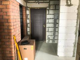 Repair construction in a new building with a free plan, in an apartment without repair with walls of red brick and gas silicate blocks door boxes and electricians photo