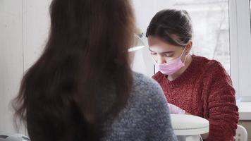 flicka i de rosa nagel tekniker en medicinsk mask och handskar framställning manikyr till en klient på de skönhet salong. de nagel vård. video