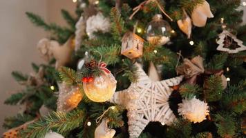 primer plano, una mujer irreconocible decora un árbol de navidad con bolas festivas. luces cálidas de guirnaldas parpadean en el fondo. vacaciones año nuevo. ambiente invernal, concepto de tradición. video