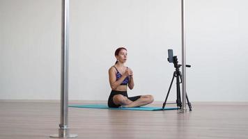 Athletic woman fitness trainer conducts workout online by filming video on a mobile phone. Remote learning and training. Remote business concept.