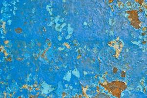 The texture of the iron metal painted blue paint old battered scratched cracked ancient rusty metal sheet wall with corrosion. The background photo