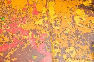 Texture of iron metal painted multicolored red yellow peeling paint of old battered scratched cracked ancient rusty metal sheet wall with corrosion. The background photo