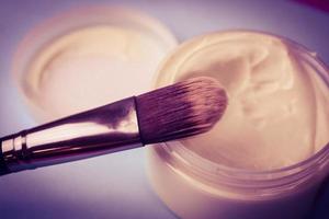 A beauty box with a wooden brush made from natural hard lint for a tone and a round jar of cream, a make-up base with a second skin effect on a blue background. Flat lay. Top view photo