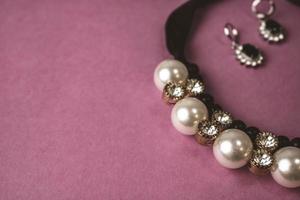 Beautiful expensive precious shiny jewelry fashionable glamorous jewelry, necklace and earrings with pearls and diamonds, diamonds on a pink purple background. Flat lay, top view, copy place photo