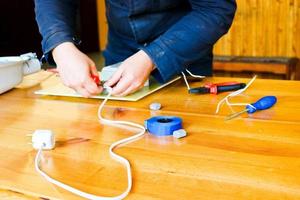 un electricista que trabaja, recoge el circuito eléctrico de una gran farola blanca con cables, un relé en una fábrica de plantas industriales foto