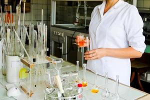 una asistente de laboratorio, doctora, química, trabaja con matraces, tubos de ensayo, hace soluciones, medicinas, mezcla los ingredientes en el laboratorio. asistente de laboratorio lleva a cabo la investigación foto