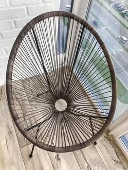 Silla ovalada de mimbre marrón con forma de huevo. material natural inusual, muebles para casas de verano. un sillón acogedor para pasar tiempo al aire libre. hay un pequeño agujero en el centro de la silla foto