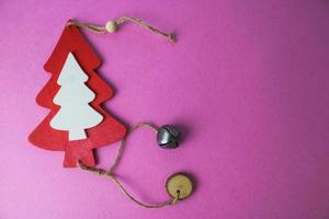 Festive Christmas winter winter happy beautiful pink purple background with a small toy wooden homemade cute Christmas tree. Flat lay. Top view. Holiday decorations photo