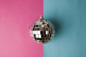 Silver mirror musical club disco ball small round glass winter shiny decorative beautiful xmas festive Christmas ball, Christmas toy plastered on glitter on a gray pink purple background photo