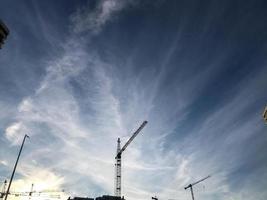 las grúas de construcción se alzan contra el fondo de un cielo azul nublado. sitio de construcción, equipo de construcción de viviendas. los constructores levantan casas altas de bloques de hormigón foto
