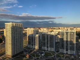 tall blue and white glass houses are lined up in height. houses are made in the same style. new microdistrict, houses with panoramic windows. against the background of dark clouds photo