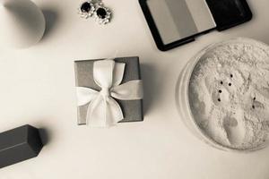 Beauty box, crumbly matte mineral powder and blush with a beauty blender for makeup and silver earrings, lipstick and gift box on a black and white background. Flat lay. Top view photo