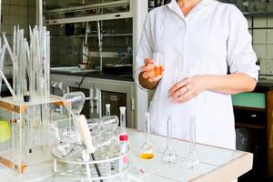 A female laboratory assistant, a doctor, a chemist, works with flasks, test tubes, makes solutions, medicines, mixes the ingredients in the laboratory. Laboratory assistant carries out the research photo