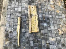 metallic yellow and rusty piece of metal lies on the asphalt. a piece of the spare part fell. construction of a new area. construction parts are scattered everywhere. next to a wooden stick photo