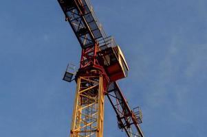 a large orange crane stands against the sky. construction crane for making concrete houses. the cabin of the master who operates the crane. a crane ladder allows the worker to climb into the cab photo