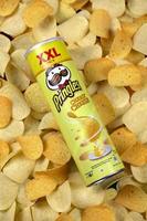 KHARKIV, UKRAINE - MAY 02, 2021 Pringles cheesy cheese flavour. Cardboard tube can on many Pringles potato chips background. Pringles is a brand of potato snack chips owned by the Kellogg Company photo