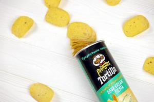 KHARKIV, UKRAINE - MAY 02, 2021 Pringles sour cream fiesta flavour. Cardboard tube can with Pringles potato chips on white table. Pringles is a brand of snack chips owned by Kellogg Company photo
