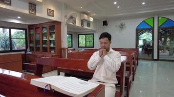 A faithful Asian young male hands in prayer gesture sitting alone on sofa at church pray and hope for good luck, success, forgiveness. Power of religion, belief, god faith, worship concept ideas. video