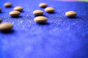 Small yellow orange beautiful medical pharmaceptic round pills, vitamins, drugs, antibiotics on a blue background, texture. Concept medicine, health care. Flat lay, top view photo