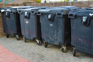 garbage containers are in the city. black capacious containers for storing various garbage in the city center. separate collection of secondary waste and repair products photo