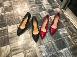 zapatos de tacón alto de cuero glamurosos, clásicos, elegantes, de mujer, negros y rojos, tacones de aguja contra un suelo gris piedra con baldosas de cerámica foto