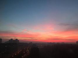 hermoso amanecer rojo del sol en una gran metrópolis de la ciudad con edificios y nubes. la vista desde la altura foto