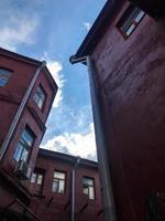 edificios rojos, un acogedor patio para salir y pasar tiempo en un café. las casas se colocan en las esquinas entre sí. hay tuberías de drenaje en las casas para drenar el agua hacia el sistema de alcantarillado foto