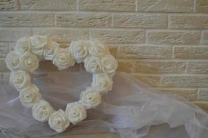 White heart with white roses and rhinestones on a background of beige bricks. photo