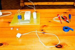 Electrical circuit with wires and spare parts, installation equipment, pliers, blue electrical tape, screwdrivers on the table photo