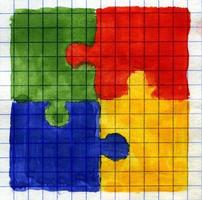 Painted colored puzzle pieces on math paper. photo