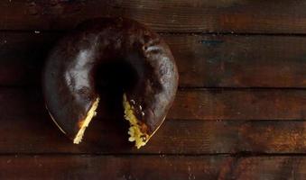 Bitten chocolate donut on wooden background. photo