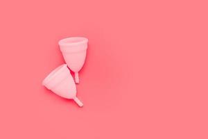 Pink menstrual cup on color background, female intimate hygiene period products, top view photo