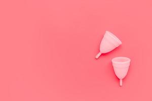 Pink menstrual cup on color background, female intimate hygiene period products, top view photo