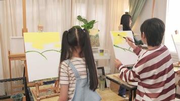 un groupe d'enfants asiatiques se concentre sur la peinture acrylique sur toile au pinceau dans une salle de classe d'art et apprend de manière créative avec talents et compétences à l'école primaire. video