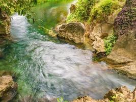 hermosa agua clara que fluye en el lago o río y entorno frente a la cueva de tham chang ciudad de vangvieng laos. ciudad de vangvieng la famosa ciudad de destino de vacaciones en lao. foto