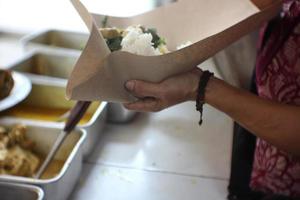 An old Indonesian woman is preparing Padang dishes for customers. Padang cuisine is a traditional food from Indonesia photo