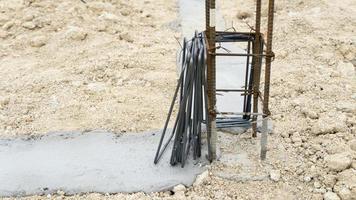 La barra de refuerzo rectangular es un punto de conexión para reforzar la resistencia de la construcción. coloque las columnas del marco de acero en el piso de cemento. construcción de los cimientos de la casa. foto