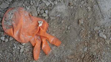 Orange rubber gloves that fell on the floor. The gloves left after the construction work were mixed with a lump of cement. photo